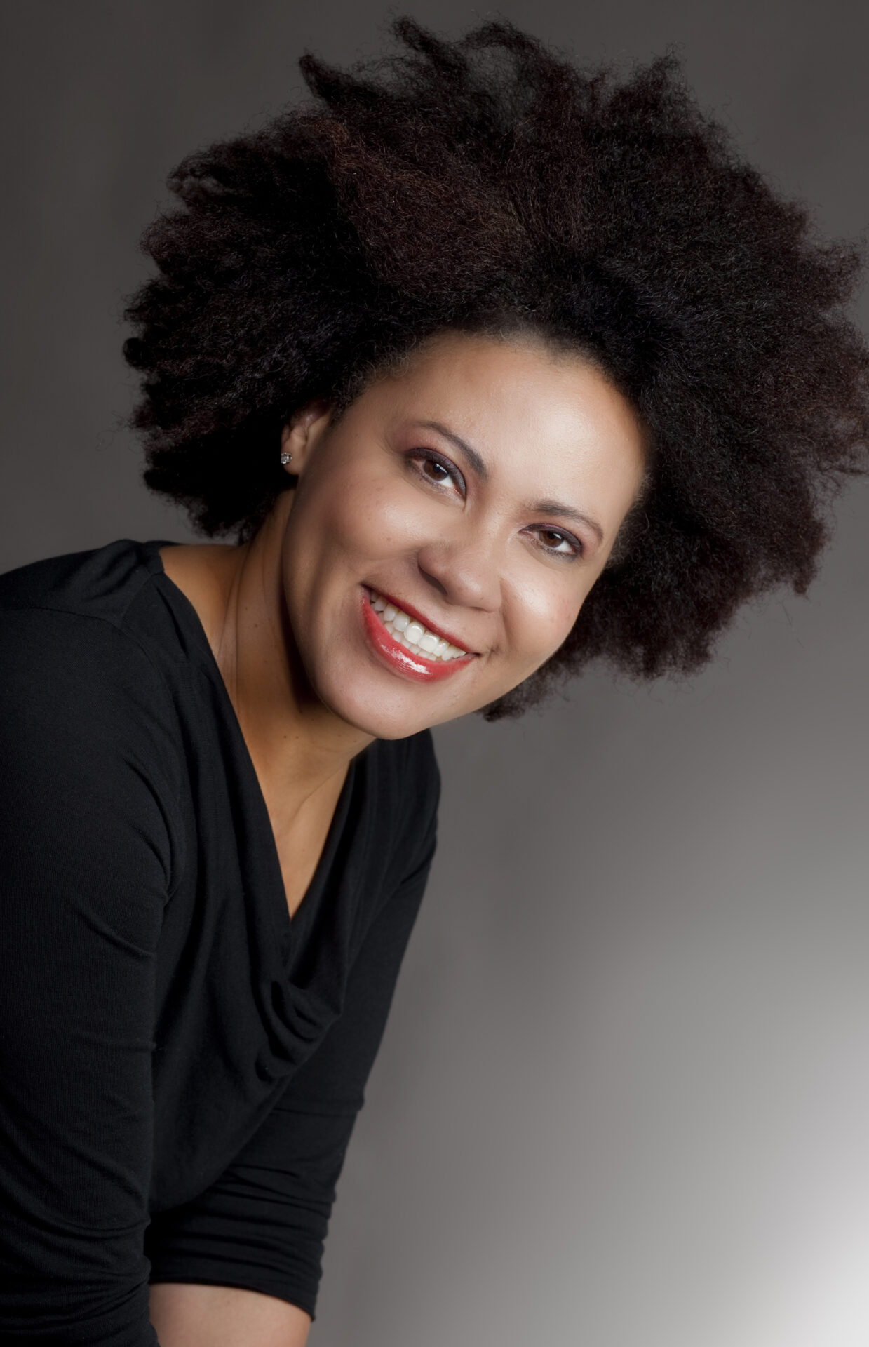 A woman with afro hair smiling for the camera.