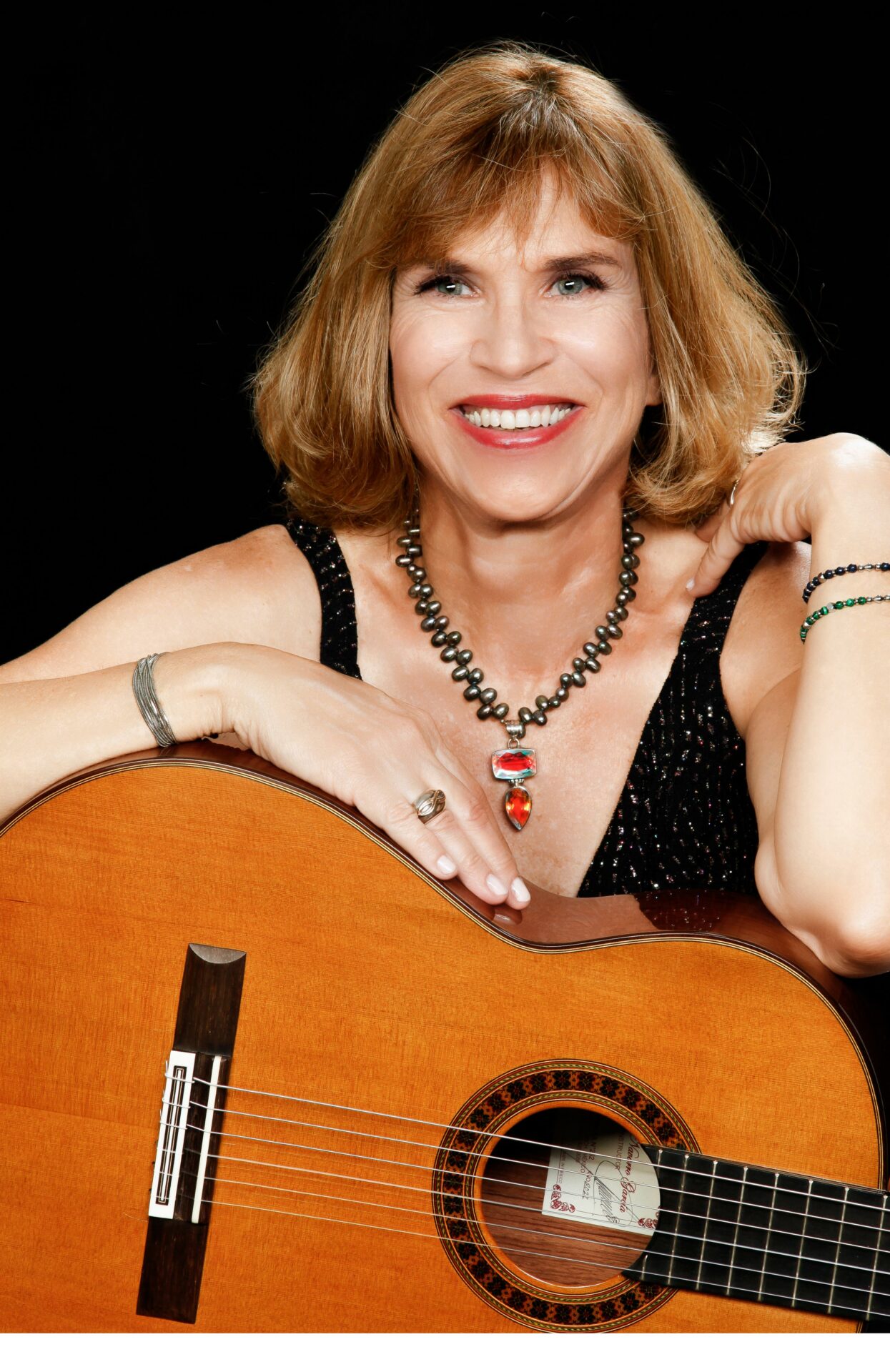 A woman posing with an acoustic guitar.