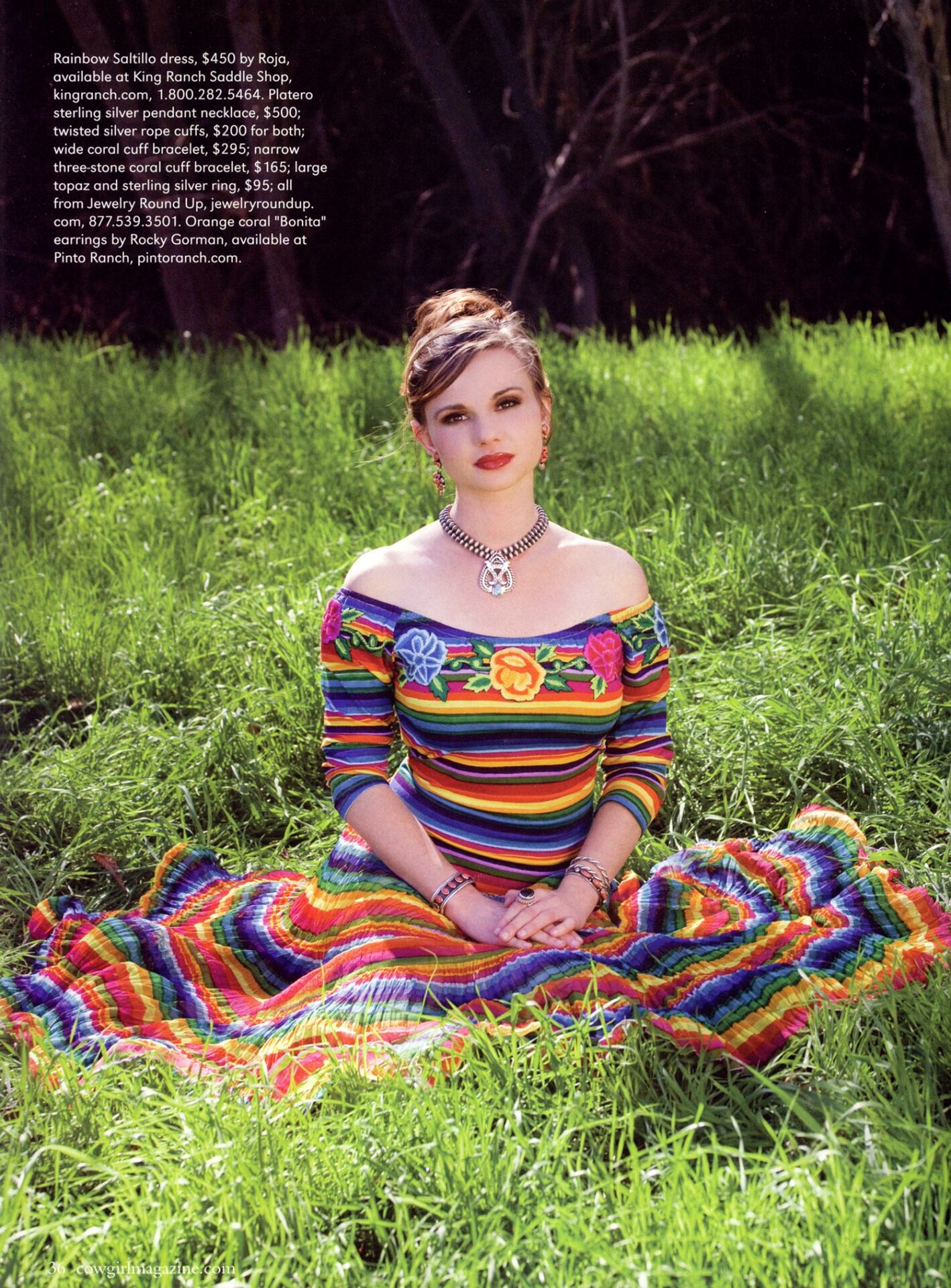 A woman in a colorful dress sitting in the grass.