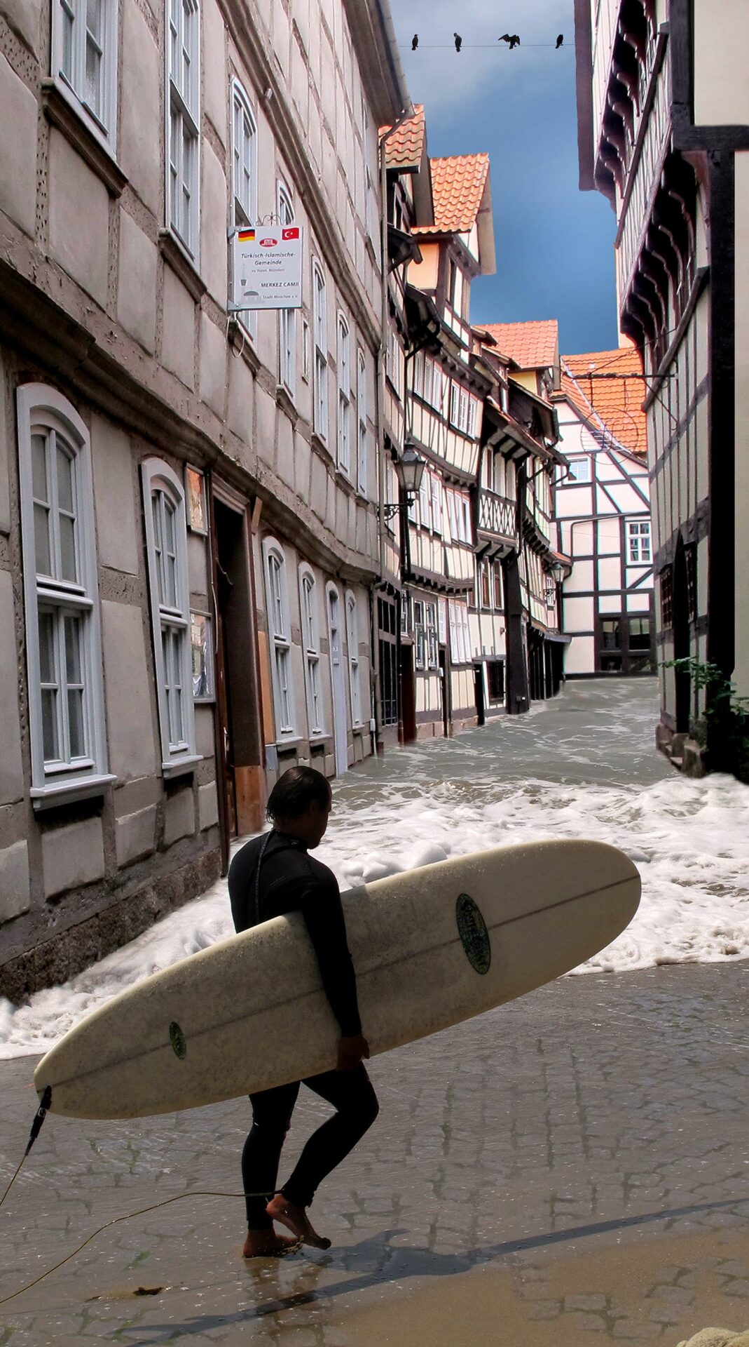 A man carrying a surfboard on a flooded street.